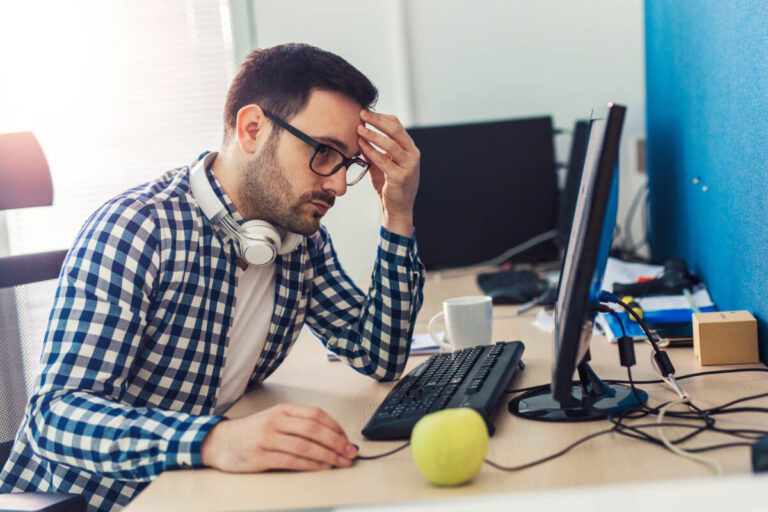 UK tech worker sitting at desk looking worried