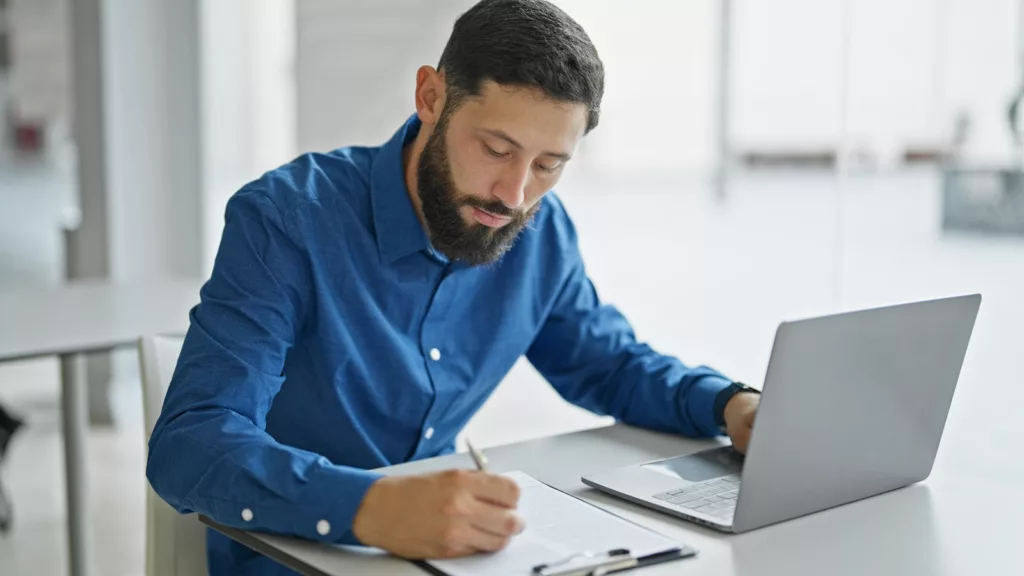 cyber essentials audit man taking notes next to laptop