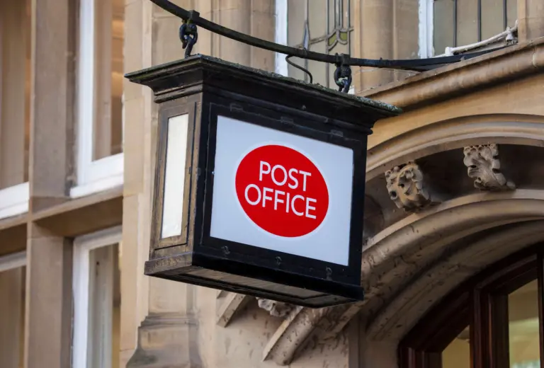 A Post Office sign hanging above a doorway - who is to blame for post office scandal