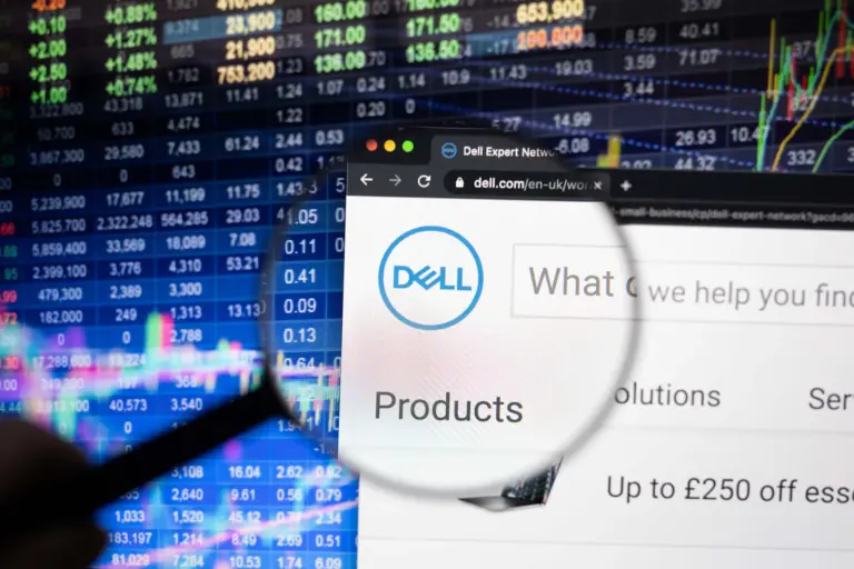 dell fiscal 2024 graphic - Dell company logo on a website with blurry stock market developments in the background, seen on a computer screen through a magnifying glass