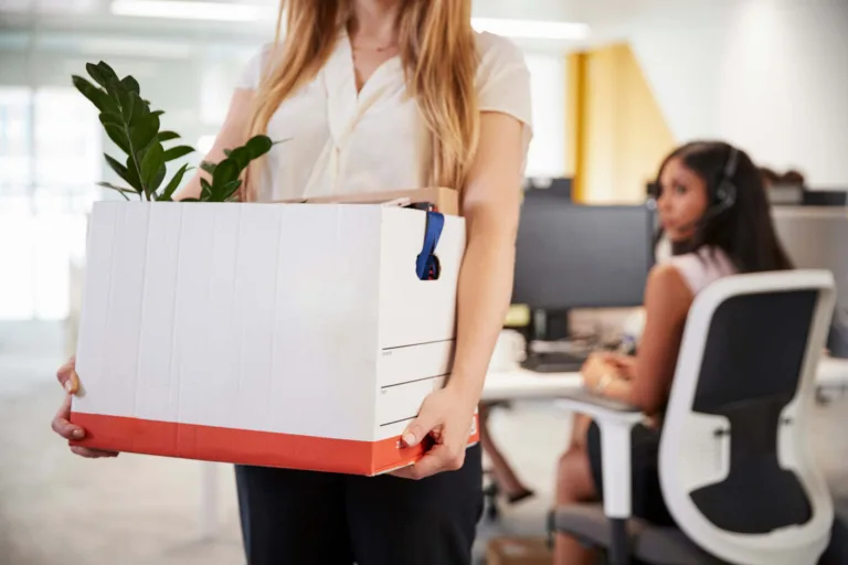AI effect on women's jobs shown by woman taking belonging box out of office