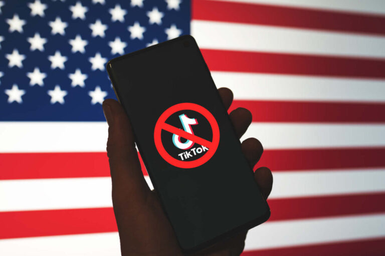 ByteDance Tiktok ban in the US represented by TikTok app logo crossed out with red Ban sign displayed on phone screen with the US flag background