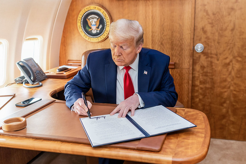 President Donald J. Trump signs an Executive Order Delegating Authority Under The Defense Production Act To The Chief Executive Officer Of The United States International Development Finance Corporation To Respond To The COVID-19 Outbreak Thursday, May 14, 2020, aboard Air Force One en route to Lehigh Valley International Airport in Allentown, Pa. (Official White House Photo by Shealah Craighead)