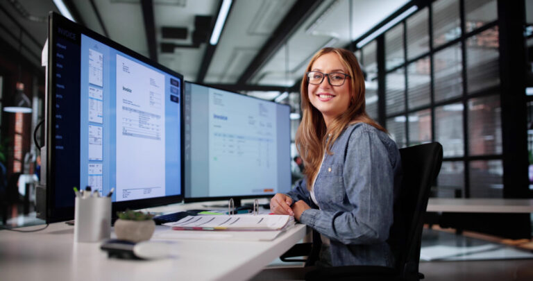 Boost small business productivity shown by Professional Woman Analyzing Invoices On Computer Screen For Financial Audit