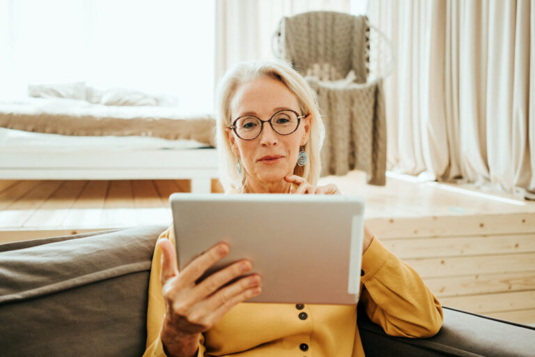 Oracle Patient Portal illustrated by mid aged woman at her bright and sunny apartment using portal with tablet computer