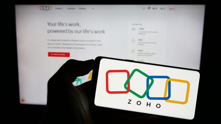 Zoho Dell AI Factory partnership shown by person holding phone with Zoho logo and laptop with Zoho.com in the background