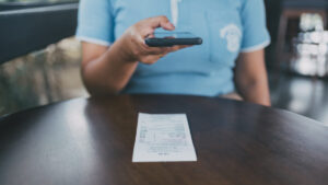ai fake receipts shown by woman scanning a receipt with a smartphone at a cafe