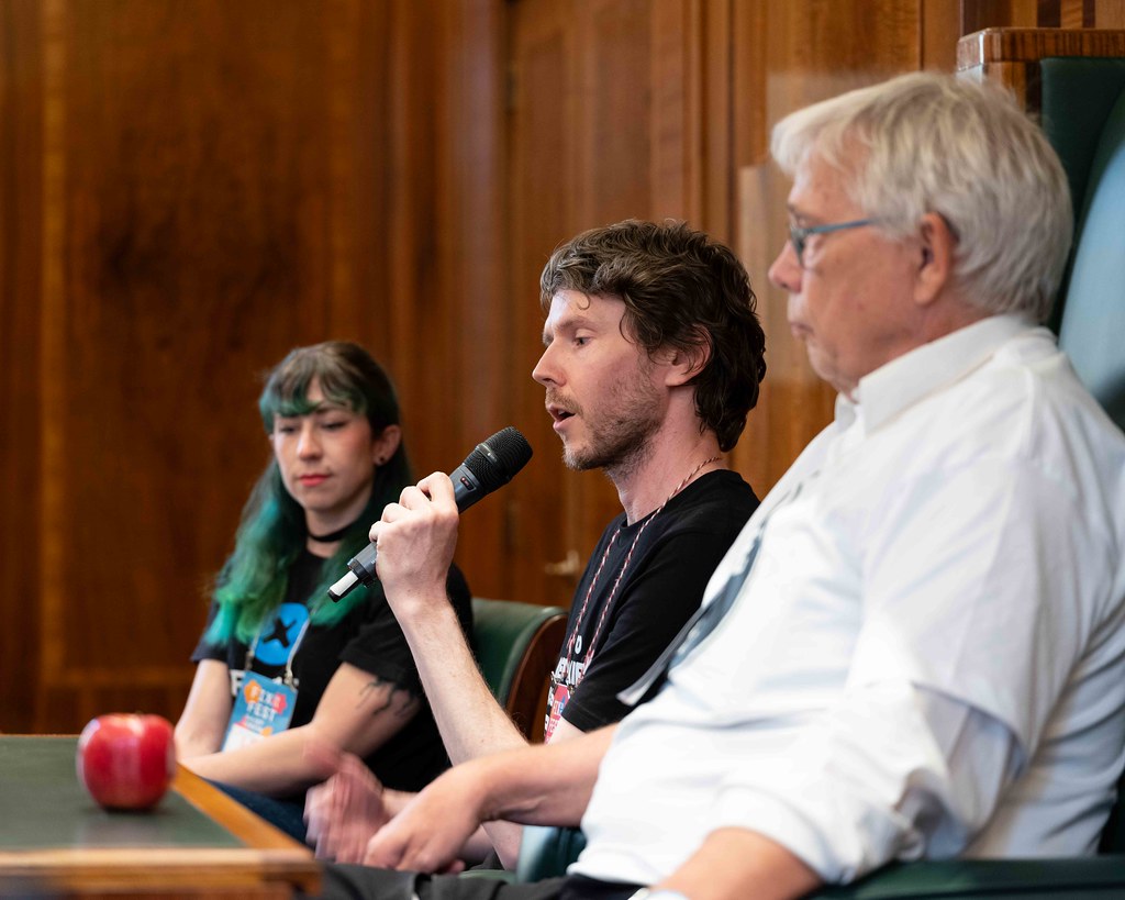 Photo is The Open Repair Alliance's Neil Mather, speaking into a Microphone at FixFest 2025