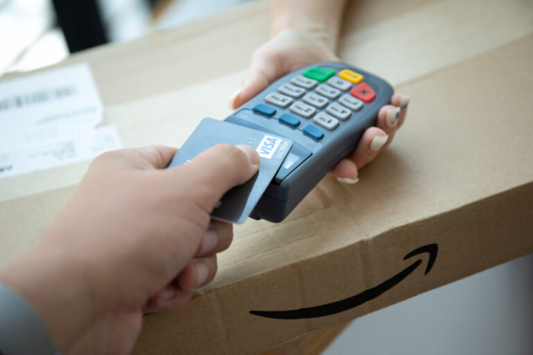 AWS Visa Agentic AI shown by man's hand holding plastic card Visa and pay pass online POS terminal Amazon Parcel