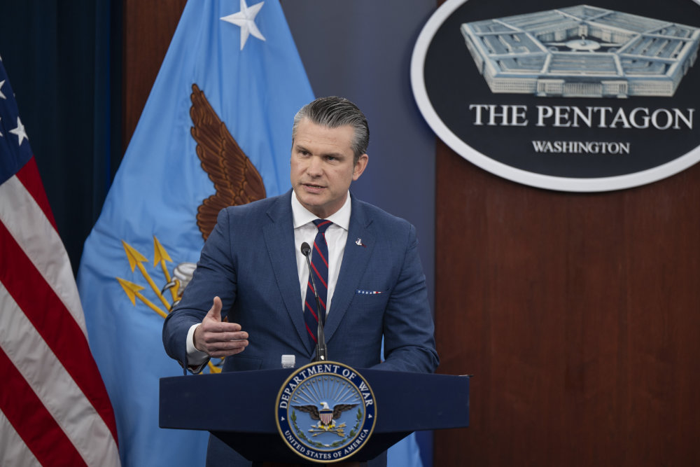 Pete Hegseth speaking at a podium in front of a Pentagon sign.