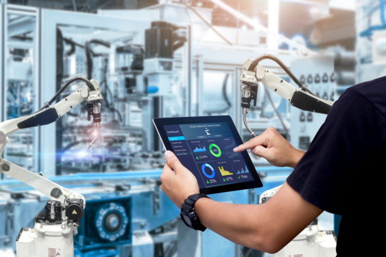 Syspro Evocon ERP shown by smart industry control concept: hands holding tablet on blurred automation machine as background