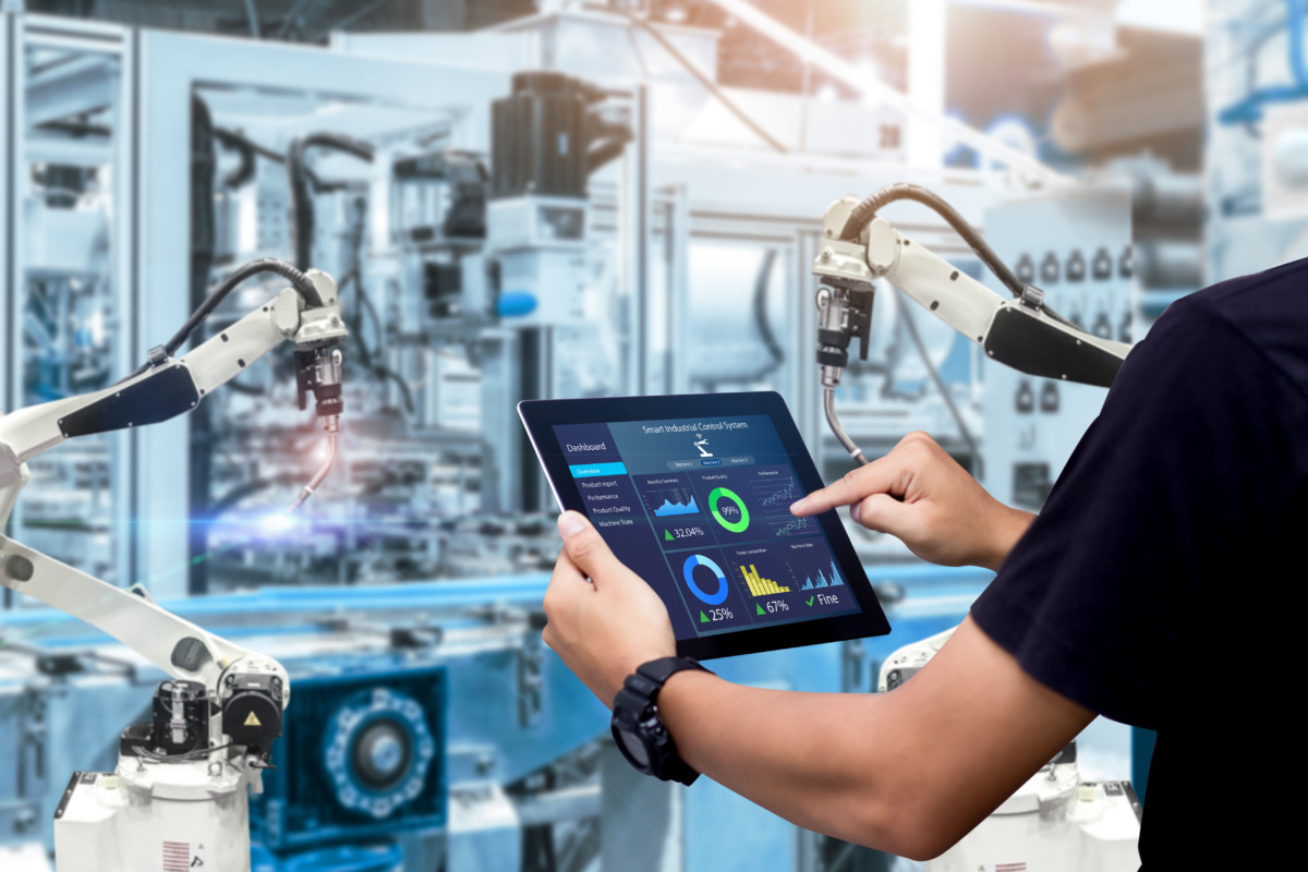Syspro Evocon ERP shown by smart industry control concept: hands holding tablet on blurred automation machine as background
