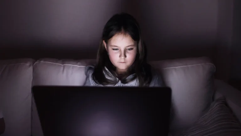 facial recognition trust shown by girl sitting in dark using laptop