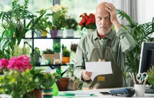 accounting mistakes illustrated by photo of a shocked flower shop owner with a bill in his hands