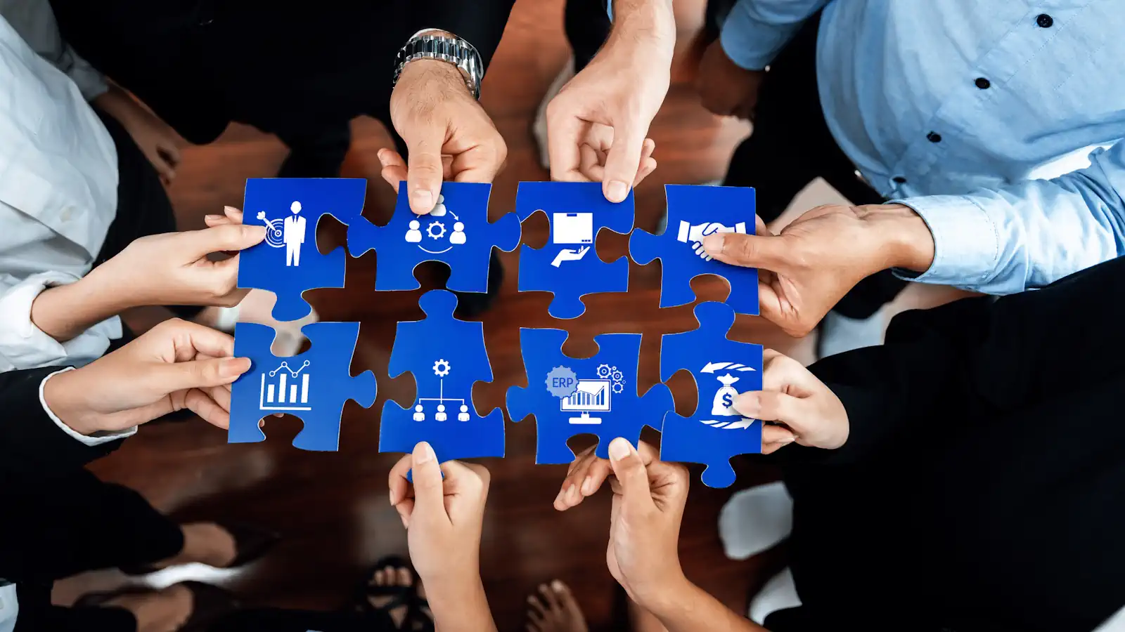 AI-ready ERP shown by diverse hands assembling colorful puzzle pieces, each piece displaying business-related icons