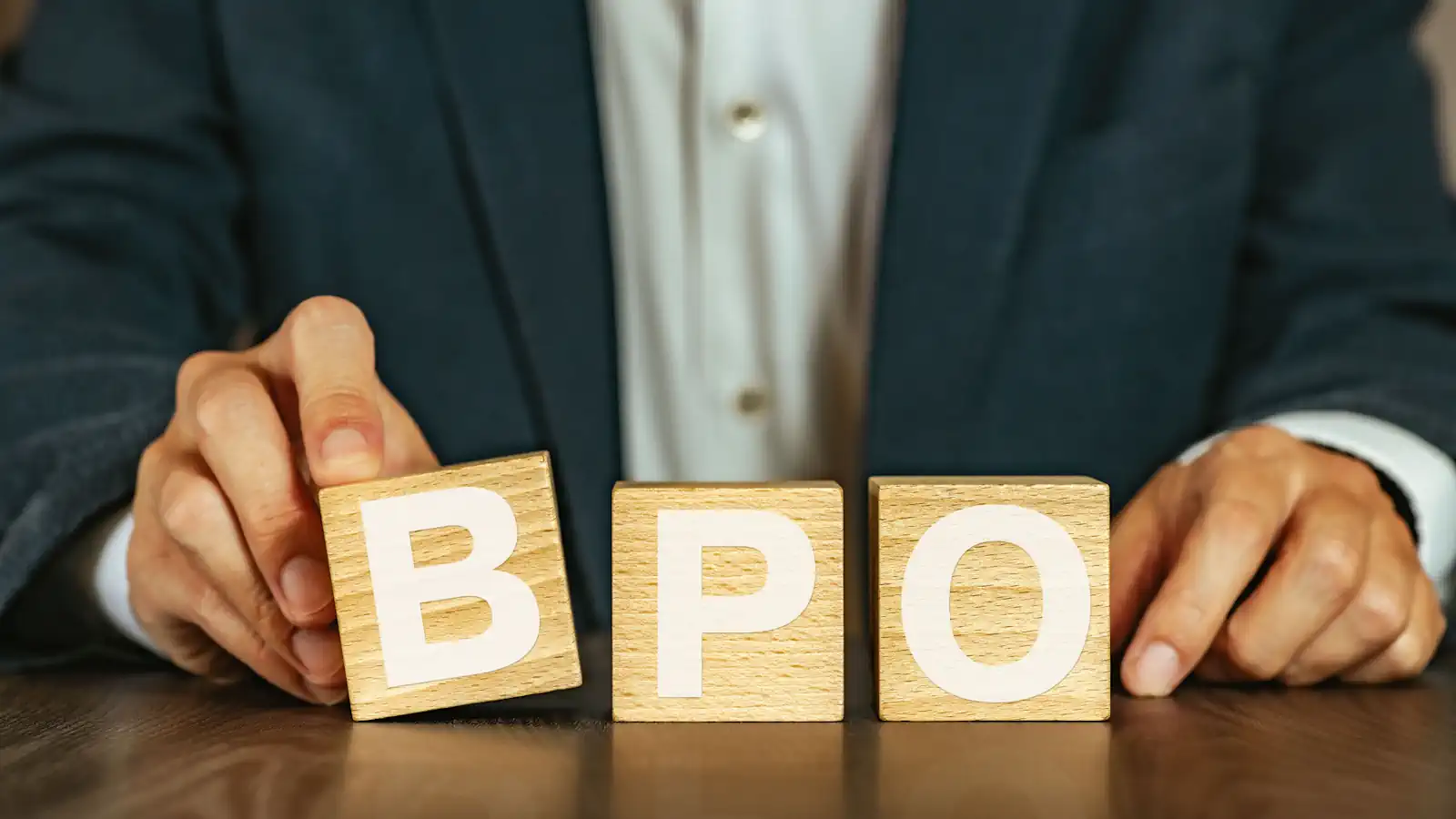 Man at desk with wooden blocks in front of him spelling BPO